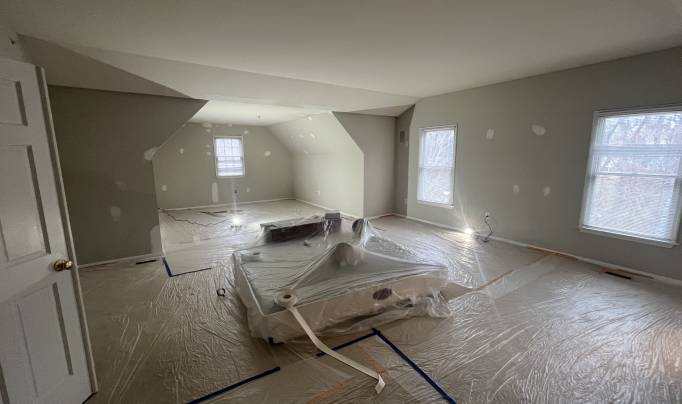 Image of a room being painted with furnitures being covered