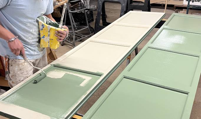 A man painting a cabinet with color green